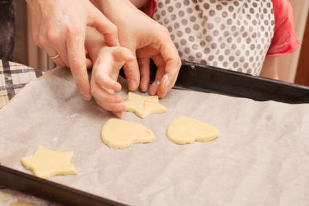 Homemade cookies with raisins on the table. Forms: circle, star, tree, heart. child helps her mother...