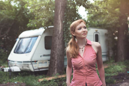 Happy young woman standing in front of camper
