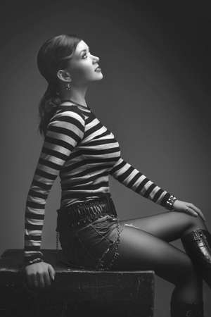 beautiful sexy slim girl posing sitting on a black cube, in gray studioの写真素材