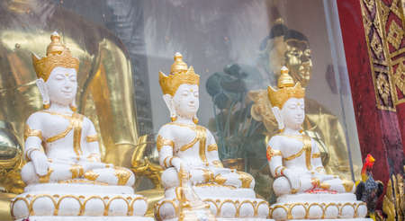 three white and golden buddha statue in the temple