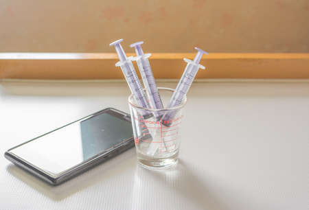 Syringe And smart phone on the hospital table