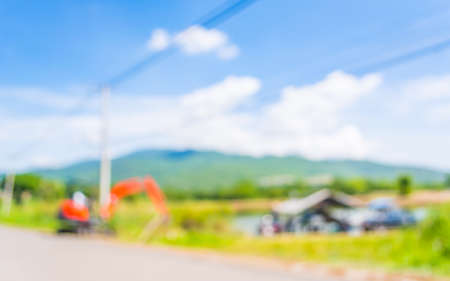 blur image of orange excavator doing lake construction and maintenance services under municipality authority on day time for background usage.の写真素材