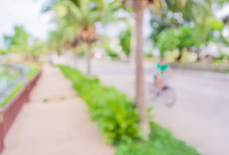 blur image of people biking on street with open space to the green garden  for background usage .の写真素材