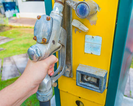 image of hand holding the gasoline tap to Refuel the car on a gas retro oil station.の写真素材