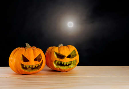 image of orange halloween pumpkin on wooden table with full moon in the sky for  background usage.の写真素材