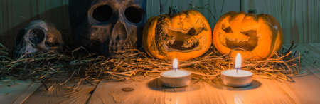 vintage tone image of rotten Halloween pumpkin with candle light and dry grass. Wooden background.の写真素材