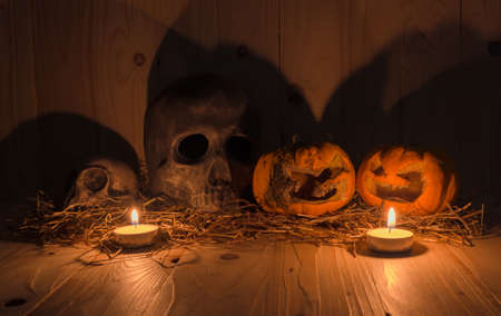 image of rotten Halloween pumpkin with candle light and dry grass. Wooden background.の写真素材