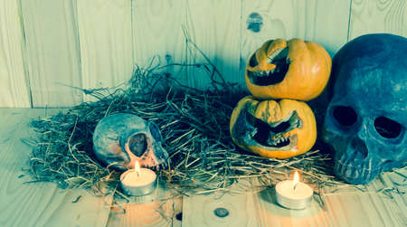 image of rotten Halloween pumpkin with candle light and dry grass. Wooden background.の写真素材
