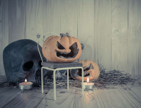 vintage tone image of rotten Halloween pumpkin with candle light and dry grass. Wooden background.の写真素材