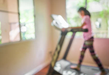vintage tone blur image of Cute girl running treadmill on day time for background usage.の写真素材