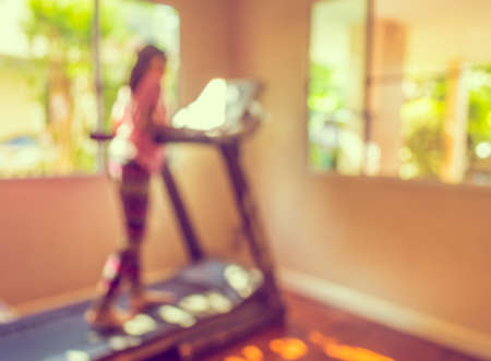vintage tone blur image of Cute girl running treadmill on day time for background usage.の写真素材