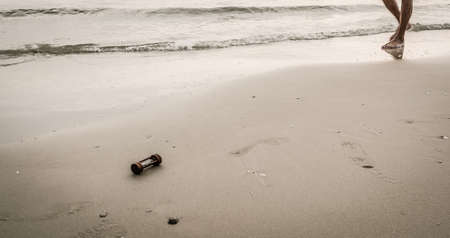 vintage tone image of sandglass on sand with wave and sea in soft focus in background. Macro with...