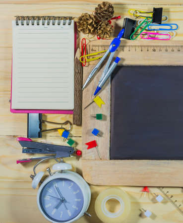 vintage tone image of wooden table top view of the chalk board with creative stationery items to...