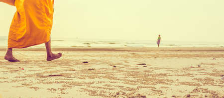 journey concept vintage tone image of blur buddhism monk and sea in background.(selective focus on sand)の写真素材