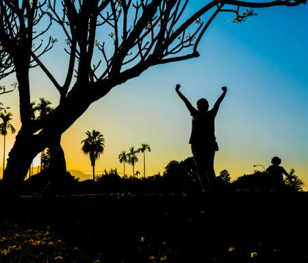 silhouette image of Happy woman in nature on sunset timeの写真素材