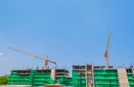 image of property construction site with cranes and clear blue sky for background usage.