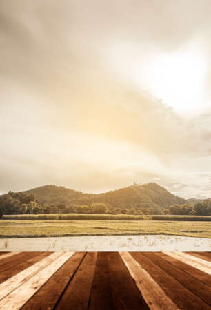 Wood pier or an old wooden table with blur image of lake and sunset sky in backgroundの写真素材