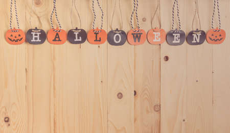 vintage tone image of paper screen "Halloween" letter and orange pumpkin with Wooden background.の写真素材