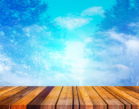 image of wood table blue sky and white clouds on day time with tree screen on sky for background usage.の写真素材