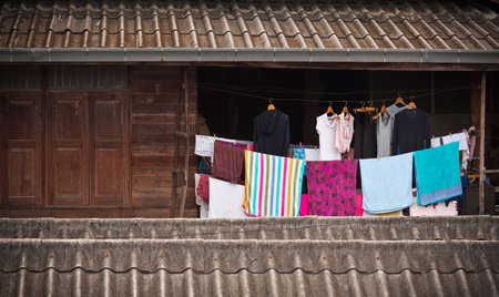 old clothes hanging on rope outside Thai style old wooden house.の写真素材