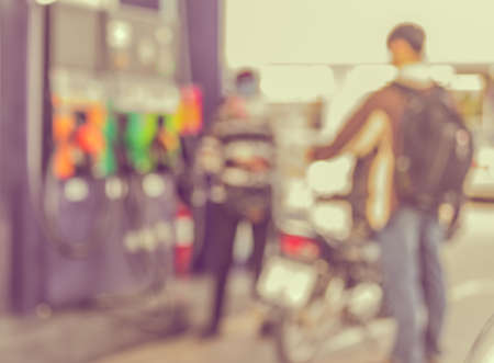blur image of people with bike at  gas station on day time for background usage.