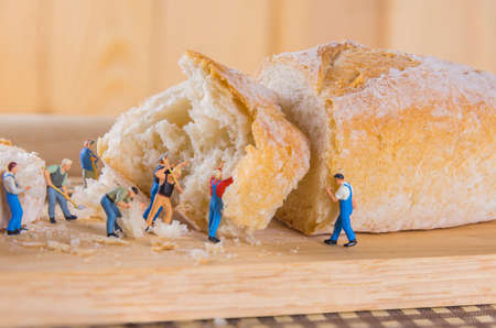 concept idea image of mini figure dolls  making French Baguette bread on slice board.の写真素材