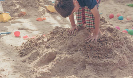 Selective focus point on hand of boy playing in sand pit for background usage.の写真素材