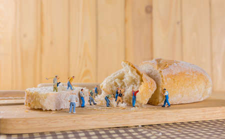 concept idea image of mini figure dolls  making French Baguette bread on slice board.の写真素材