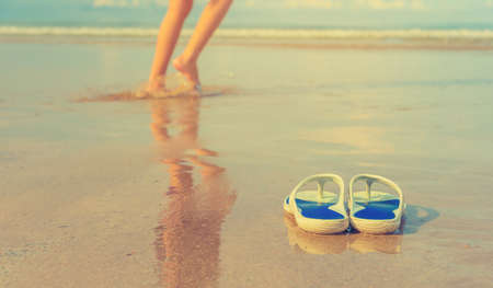 image of Flipflops on ocean beach use for Summer vacation concept background.(focus on shoes)の写真素材