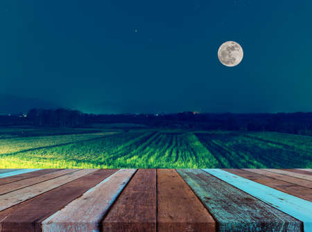 wood table and vintage tone image of the rice field on night time.の写真素材