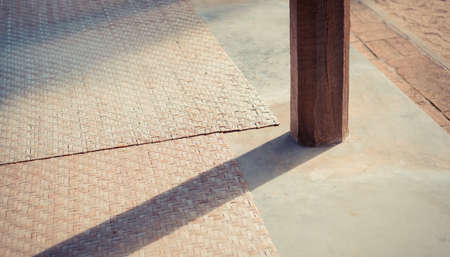 vintage tone of wood post and hand made mat on floorの写真素材