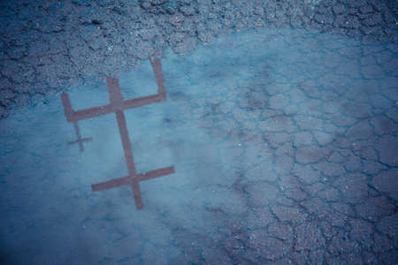 vintage tone image of Christ cross shadow reflected in water on road.の写真素材