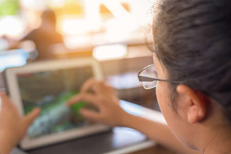 image of Asian cute girl touching on screen of tablet on table.