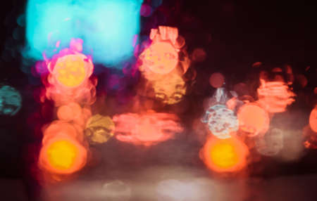 vintage tone blur image of people driving car on night time with raindrop on glass  for background usage.(take photo from inside)の写真素材