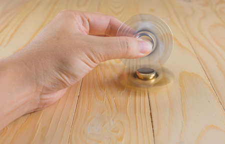 image of hand with spinner toy(fidget) on wood table.の写真素材