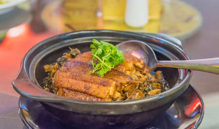 Chinese Style pork leg pot stewed in black bowl on wood.の写真素材