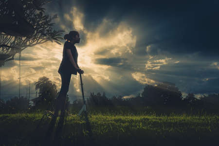 vintage tone silhouette image of Asian girl playing scooter on grass field.の写真素材