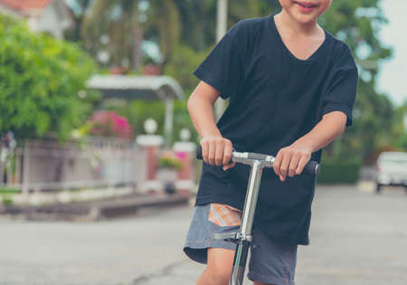 vintage tone image of Asian boy playing scooter on street.の写真素材