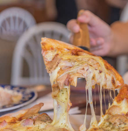 image of hand lift up cheese and ham pizza.の写真素材