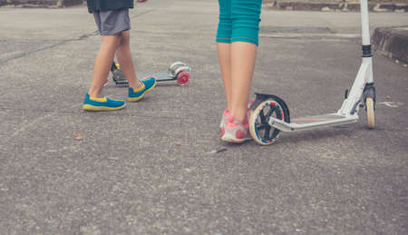 image of Asian boy and girl playing scooter on streetの写真素材