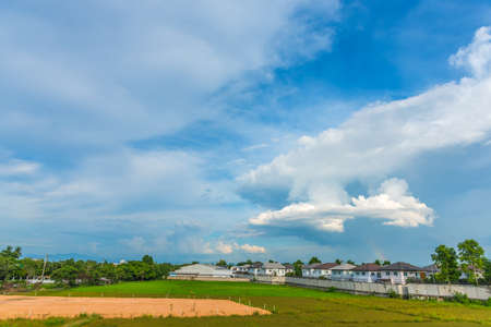 image of green field near the house in villa and cloudy blue sky for background usageの写真素材