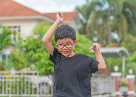 image of Asian boy in black T-shirt with funny face and joyful action in park.の写真素材