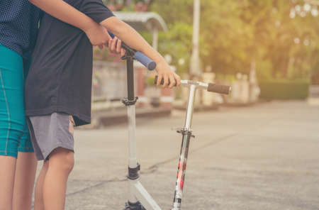 image of Asian boy and girl playing scooter on streetの写真素材