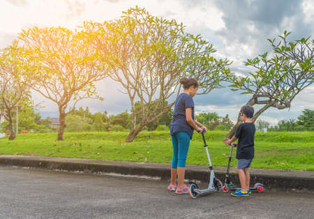 image of Asian boy and girl playing scooter on streetの写真素材