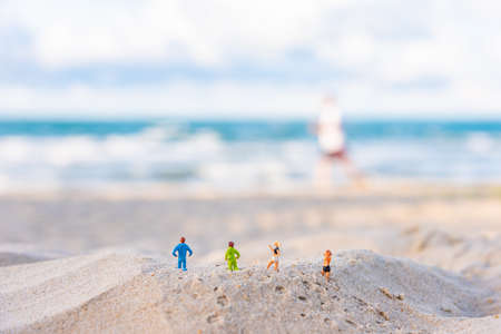 Minifigure doll idea image of four runners running on the sandy beach with blur beautiful sea on...