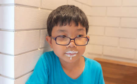 Young handsome adorable Asian boy drink frothy milk until the mouth is sloppy.の写真素材