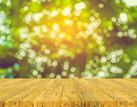 Wooden table and abstract blur image of green tree bokeh.