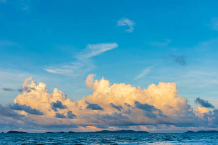 Image of the sea and the cloudy blue sky over it with an island on the horizon.の写真素材