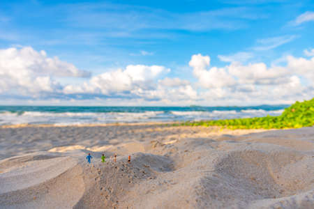 Minifigure doll idea image of four runner running on sand beach with blur beautiful sea on day time in background.の写真素材