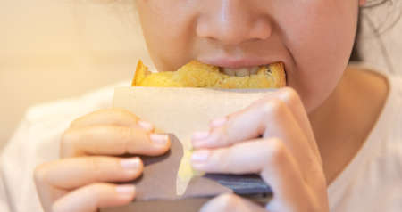 Image of Thai teenager girl biting butter bread close up on mouth.の写真素材